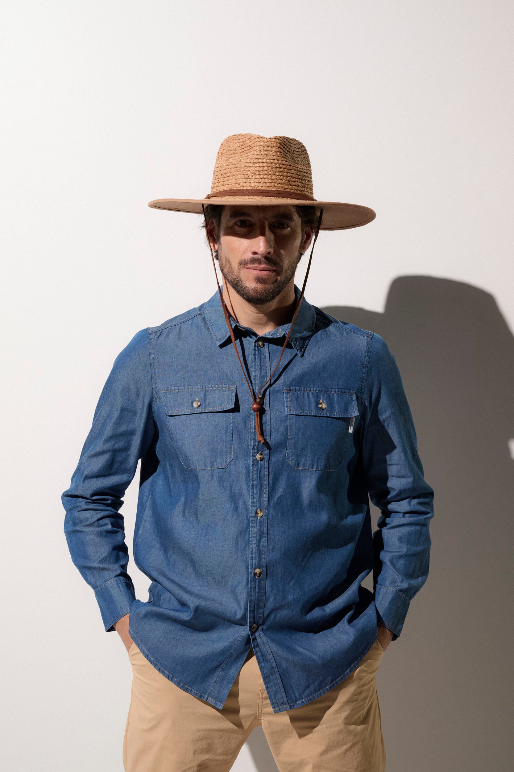 Homme portant un chapeau anti-UV UPF50+ et une chemise en denim, parfait pour une journée ensoleillée.