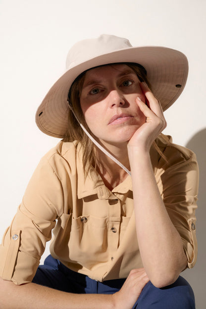 Chapeau anti-UV beige UPF50+ porté par une femme, idéal pour des activités de plein air et une protection solaire.