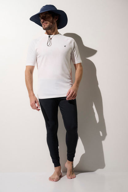 "Homme en chapeau anti-UV bleu, t-shirt blanc UPF 50+ et leggings noirs, idéal pour la protection solaire lors d'activités en extérieur."