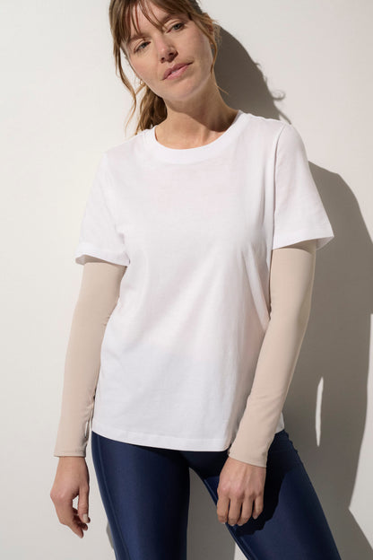 Femme portant un t-shirt blanc avec manches anti-UV beige, idéal pour les activités de plein air, UPF50+.