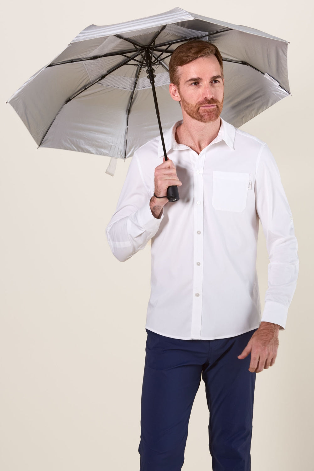 Homme portant une chemise blanche, tenant une ombrelle anti-UV, idéale pour une protection solaire quotidienne.