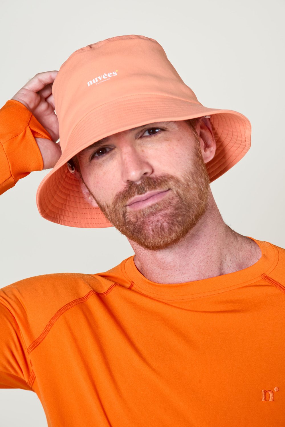 Homme portant un chapeau de pêcheur orange anti-UV avec un t-shirt à manches longues anti-UV, protection solaire.